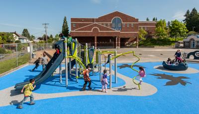 Kids at Hawthorne Elementary School playing on playground. Elementary school building in the background and surrounding neighborhood in the background.