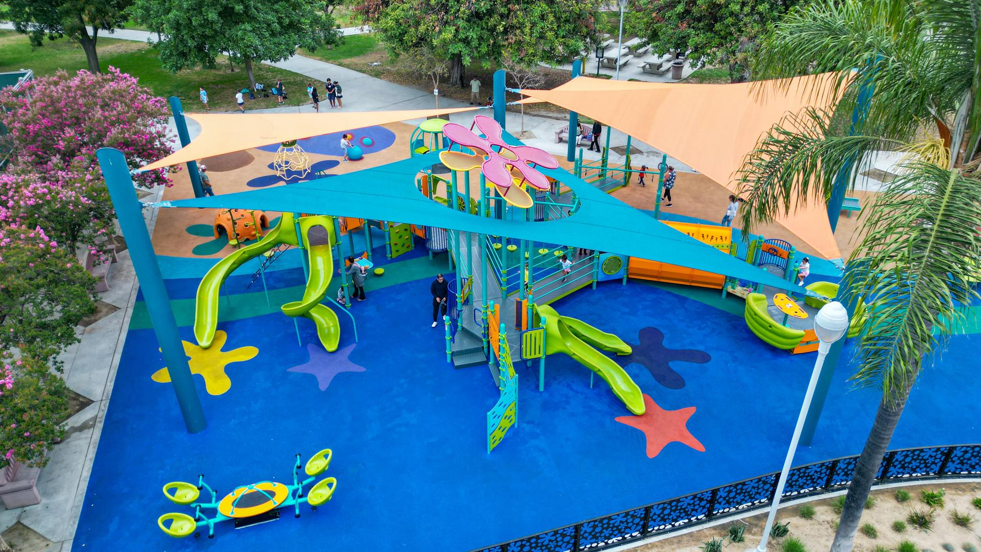 Elevated view of a ocean themed tower playground structure peaking through a port hole of a large shade system over the entire play area of the park.