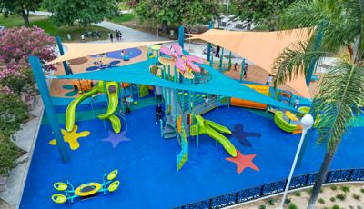 Elevated view of a ocean themed tower playground structure peaking through a port hole of a large shade system over the entire play area of the park.