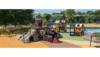 啾啾火车主题的游戏结构坐在舒适的量化社区游乐场。孩子们可以爬上有立交桥的火车，或者“进城”去市场，在围栏里“交易货物”，或者乘坐滑梯。