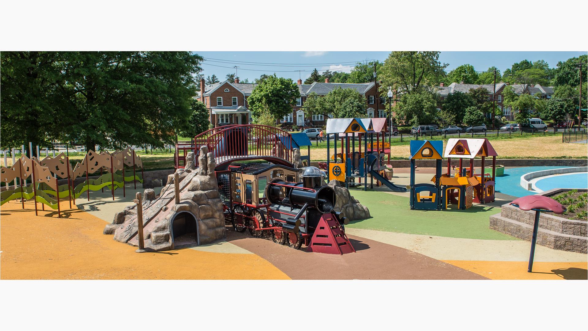 Choo choo train-themed play structures with sit snug in this quant neighborhood playground. Children can climb this train with  overpass or "go into town" to the market to "trade goods" in the enclosures or ride the slide.