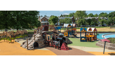 Choo choo train-themed play structures with sit snug in this quant neighborhood playground. Children can climb this train with  overpass or "go into town" to the market to "trade goods" in the enclosures or ride the slide.