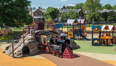 Choo choo train-themed play structures with sit snug in this quant neighborhood playground. Children can climb this train with  overpass or "go into town" to the market to "trade goods" in the enclosures or ride the slide.