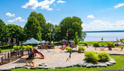 Full elevated view of a park near a lake with Viking ship themed play structures.
