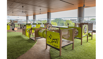 A covered balcony play area with multiple play structures and activities for toddler age children.