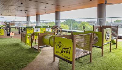 A covered balcony play area with multiple play structures and activities for toddler age children.