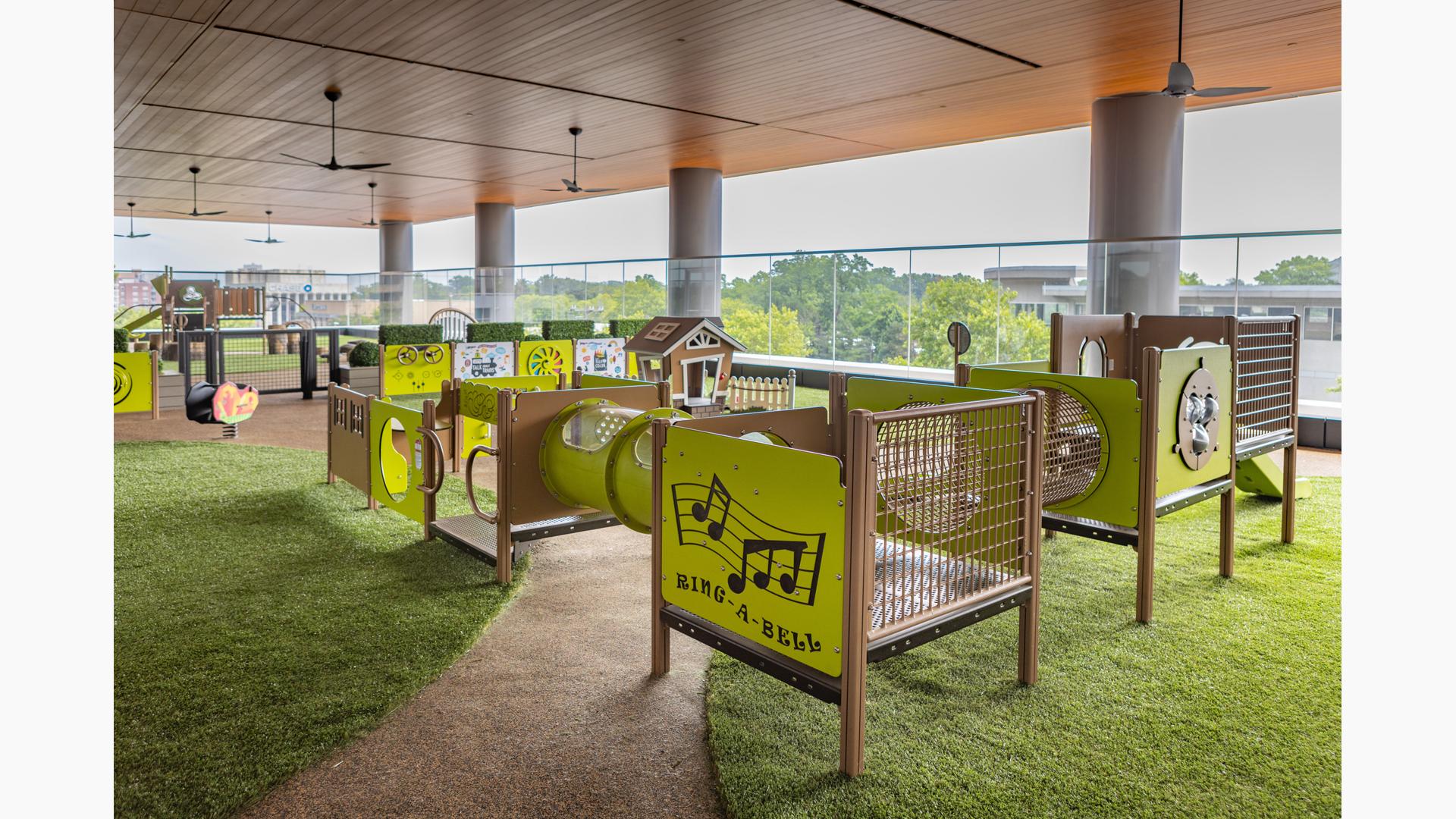 A covered balcony play area with multiple play structures and activities for toddler age children.