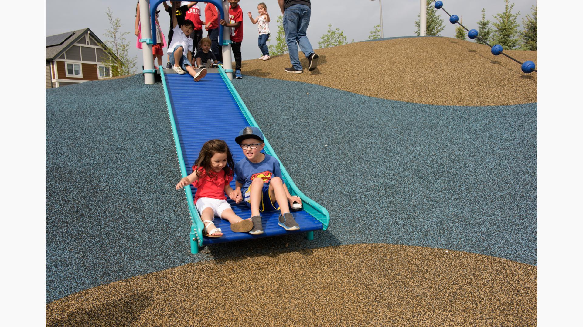 Boy and girl riding down slide