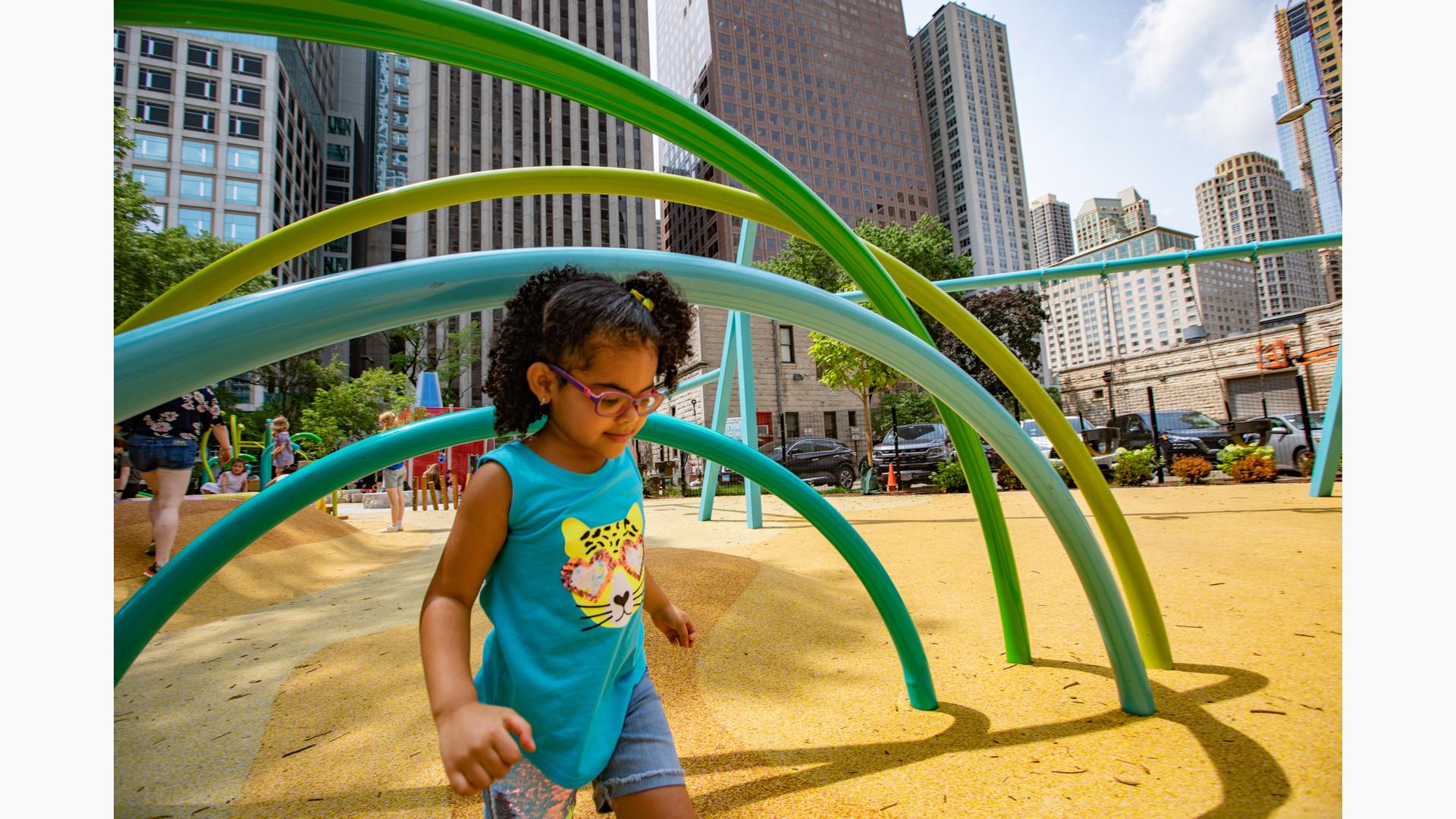 Girl walking in Seneca Park, Eli M. Schulman Playground with Chicago sky scrapers behind her