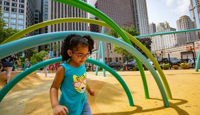 Girl walking in Seneca Park, Eli M. Schulman Playground with Chicago sky scrapers behind her