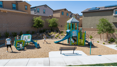 Children play at a small neighborhood park with a science themed play structure for older children with a matching color themed smaller play structure for toddlers.