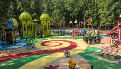 Wizard of Oz custom playground in Watkins Regional Park. A group of kids play on tractor feature, while a man walks through the play area.