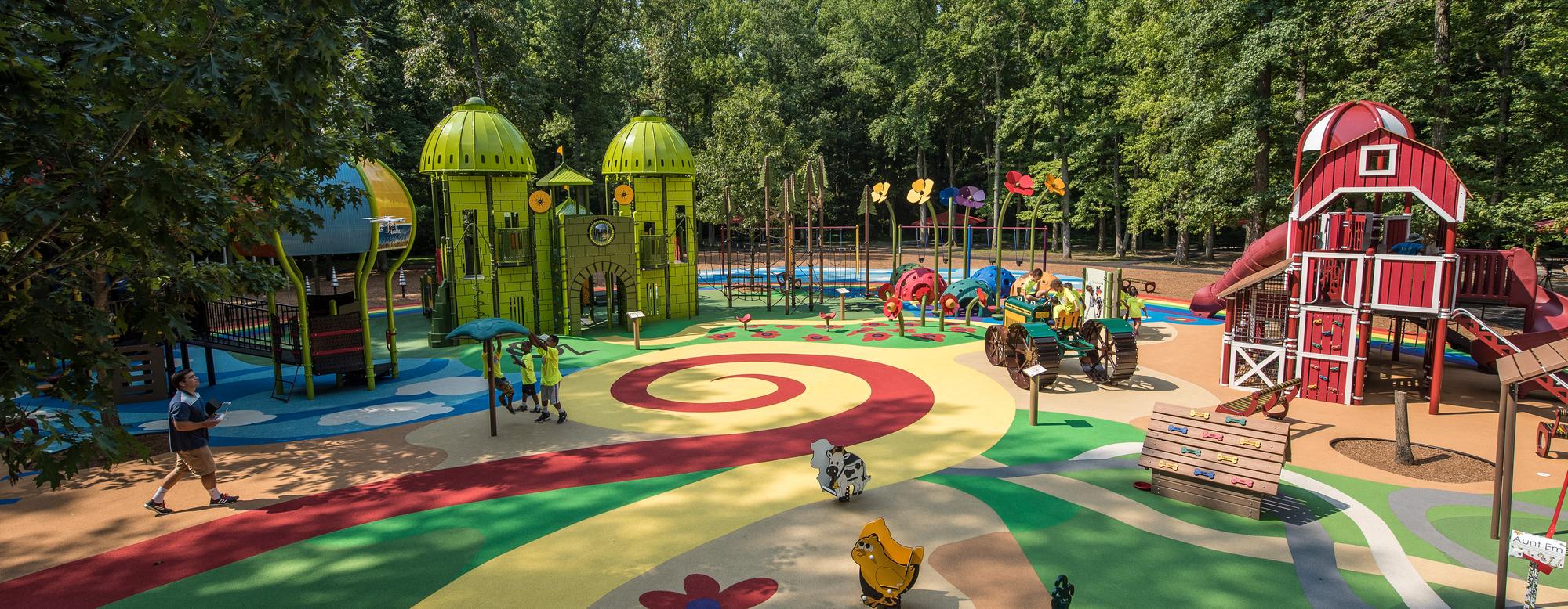 Wizard of Oz custom playground in Watkins Regional Park. A group of kids play on tractor feature, while a man walks through the play area.