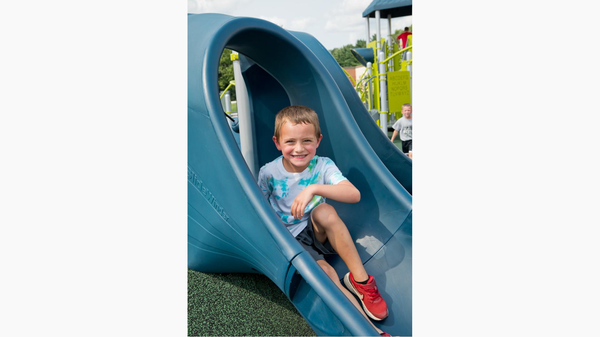 Boy sits and smiles on slide