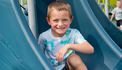 Boy sits and smiles on slide