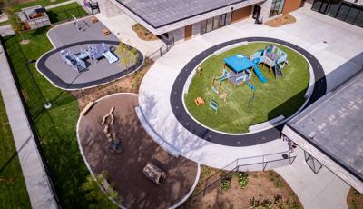 Elevated view of a school building with two separate circular play areas with one structure for toddlers while the other is for a bit older children.