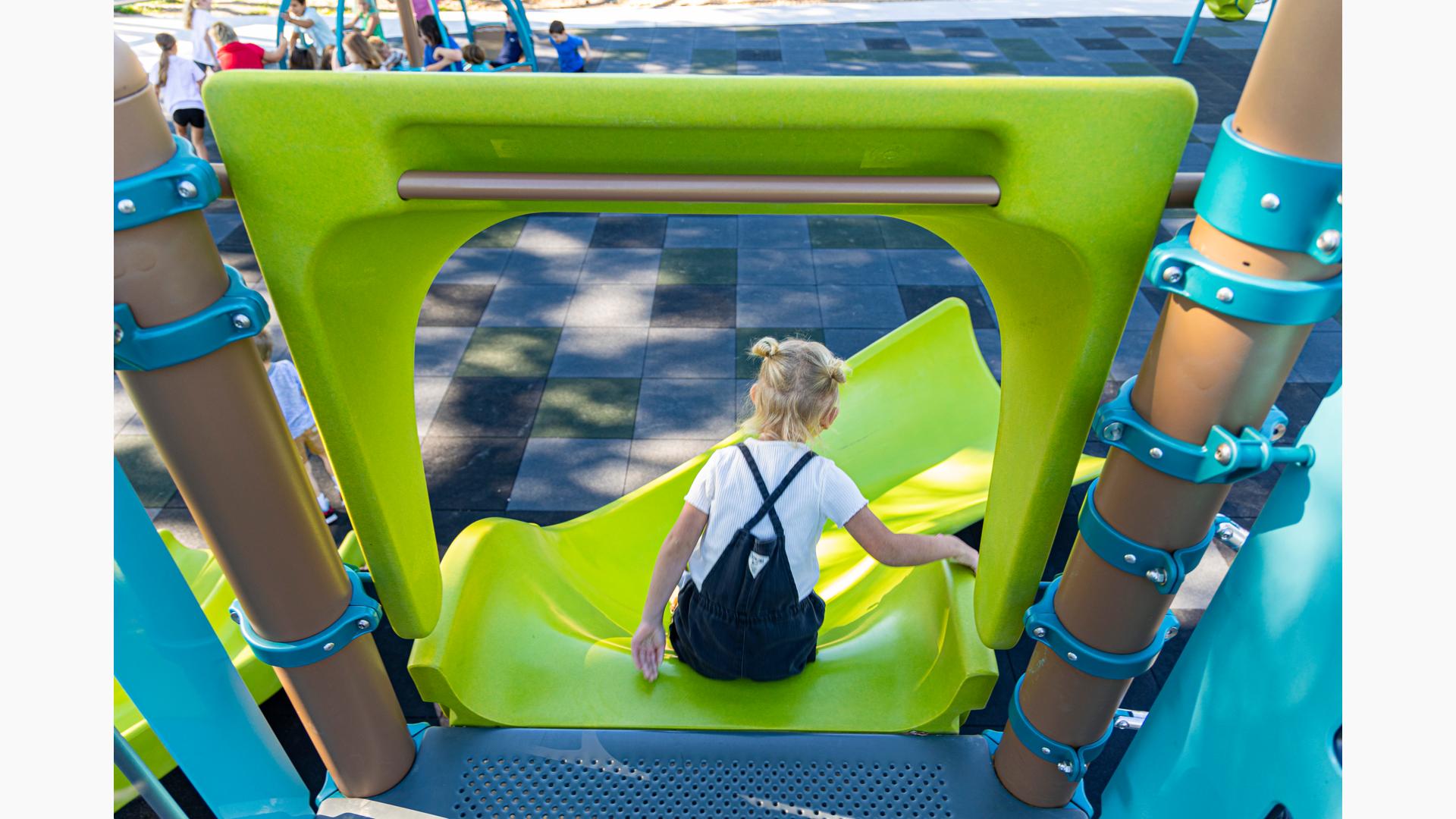 A girl sits at the top of an Alpine Slide, getting ready to slide down.