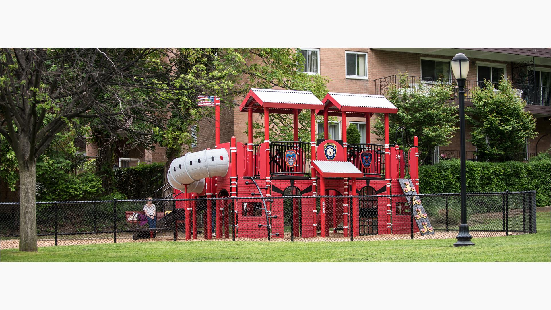  Created to honor and remember local firefighters, is a firehouse- and firetruck-themed PlayBooster® play structure. Surrounded by a black chain-link fence for children's safety and nestled in a New York neighborhood parents can watch their kids imagine life a firefighter from the comfort of their homes surrounding the park.