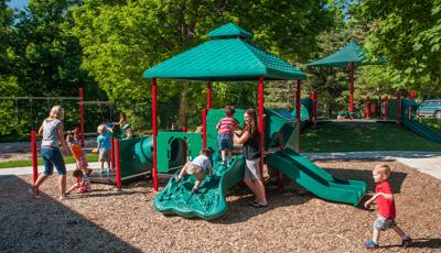 Two mothers play with children on the PlayShaper playground. Two boys climb the slide.