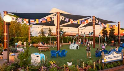 Families playing at a playground with shade sails over head.