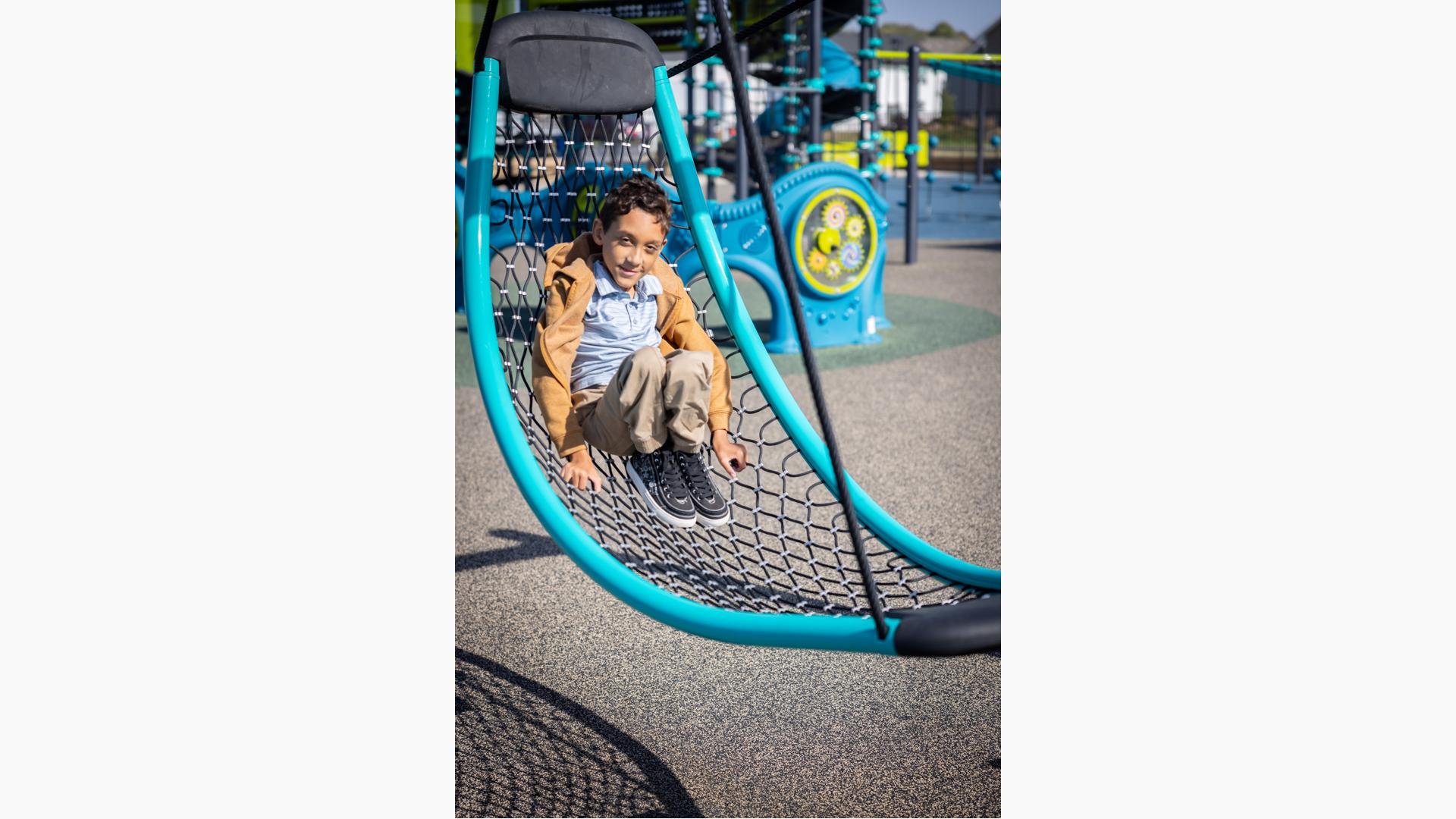 Boy sits on cable net swing