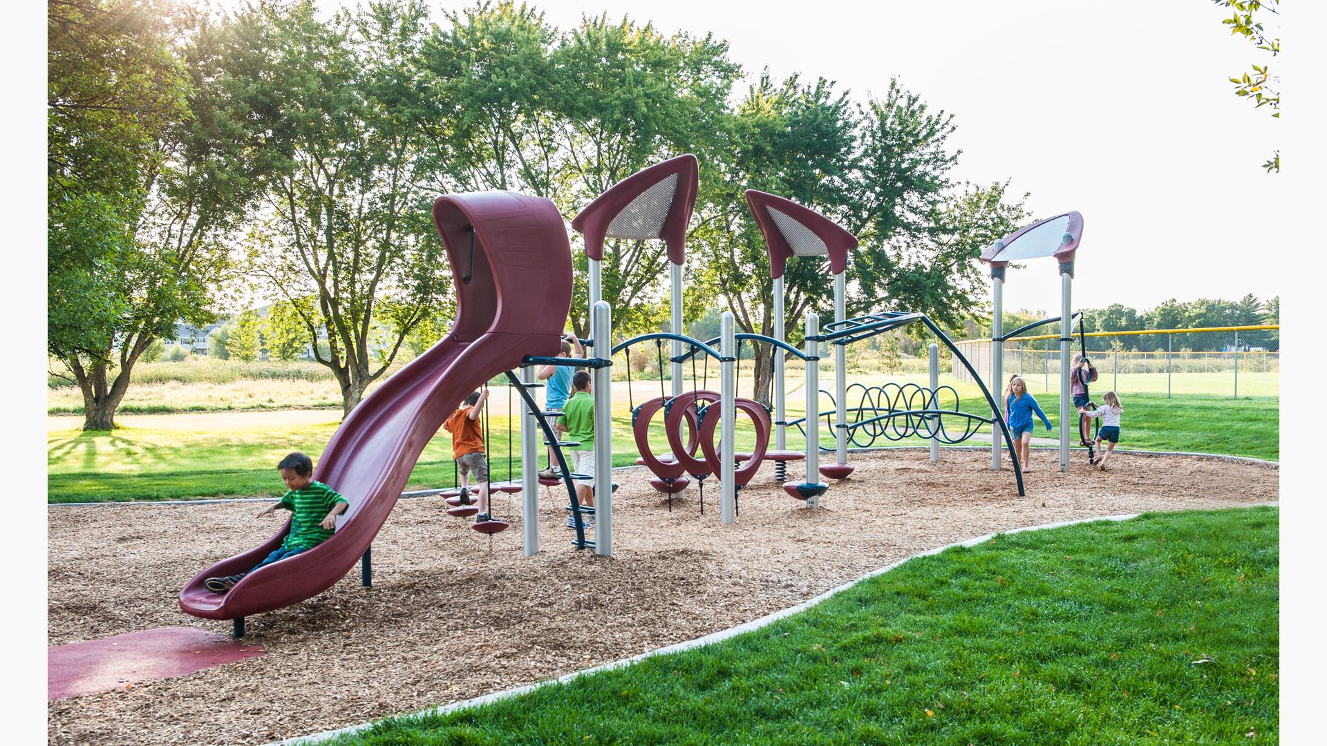 A group of children play together at a park playground.