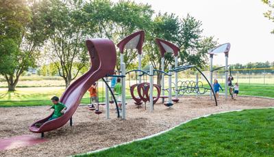 A group of children play together at a park playground.