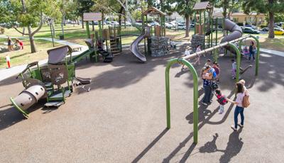 Parents play with their kids on the swings at Reservoir Park.