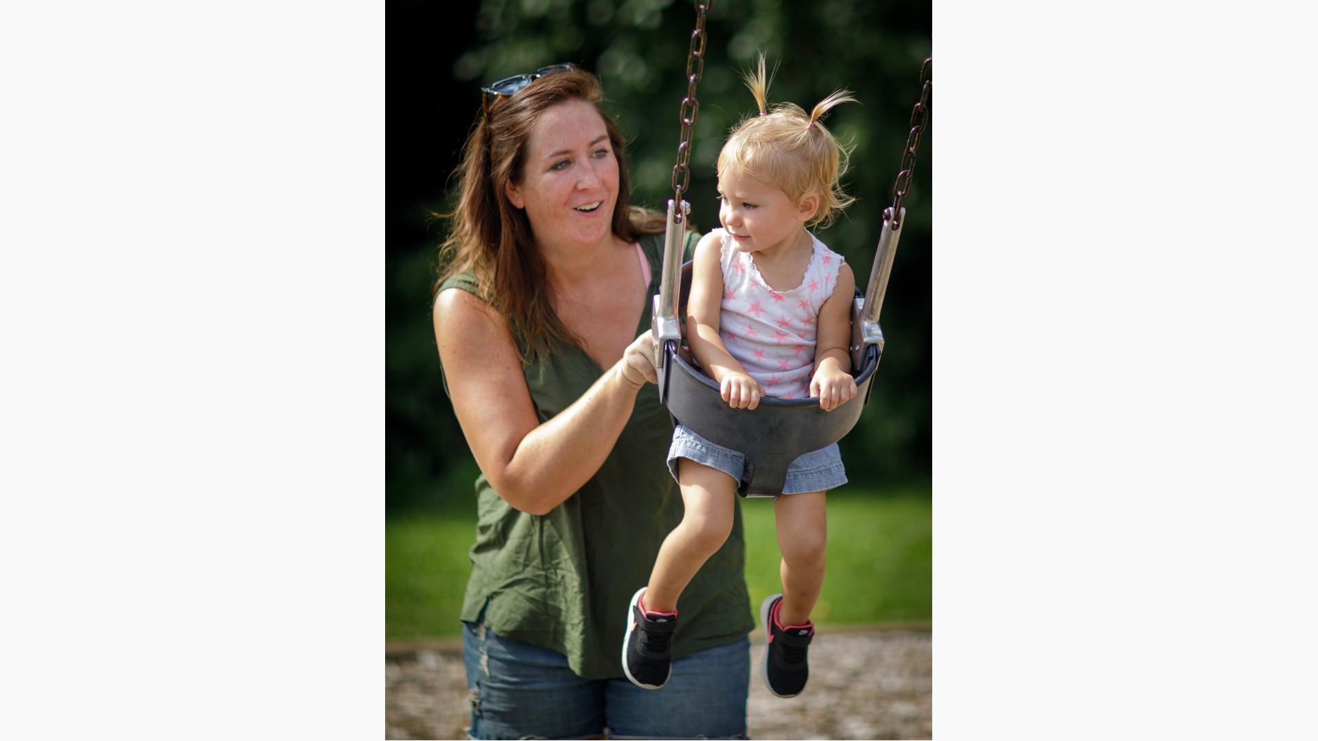 Woman pushes little girl on Full Bucket Seat w/Chains