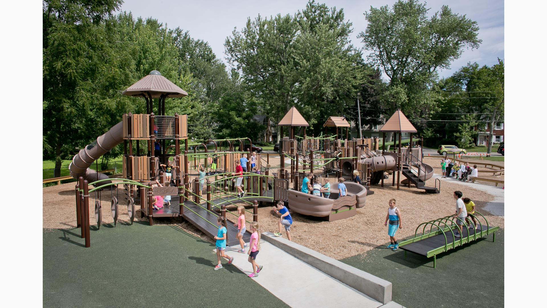 The historic Hamburg Community Playground is a busy place for kids of all ages and abilities with such play features as the Sway Fun, rock climbers from the Canyon Collection, as well as numerous slides and ramps. The Sway fun is packed with kids. Children run across the ramps and check out the many learning panels.