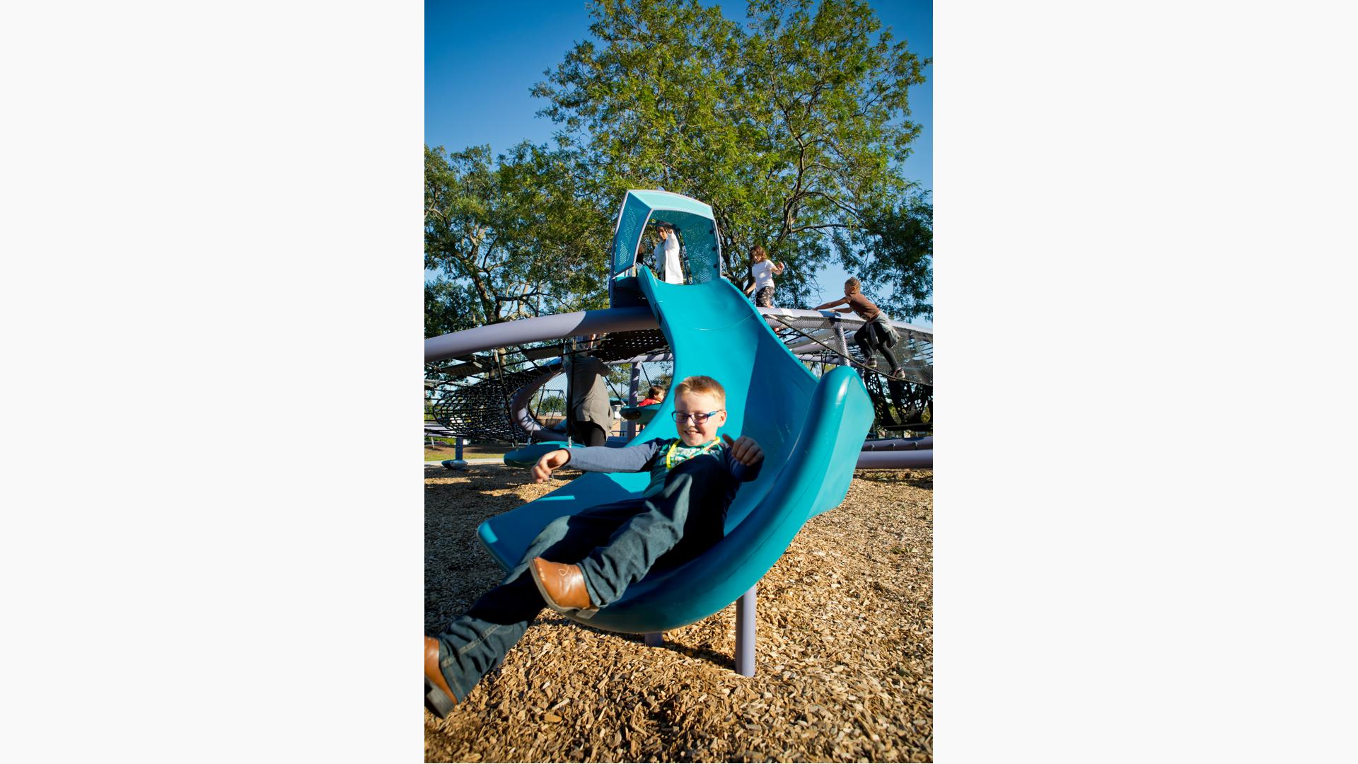 Boy having fun riding Quantis™ netplay concept slide