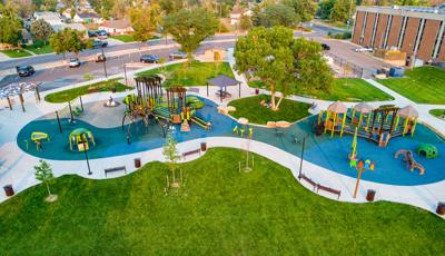 Full elevated view of a large inclusive play area with two separate nature themed play structures surrounded by additional play activities like swing sets, climbers, and outdoor musical instruments.