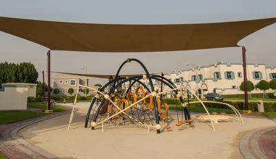 Under SkyWays shade canopy this Evos play structure sitting in  a sand playground. Freestanding riders in the distance.