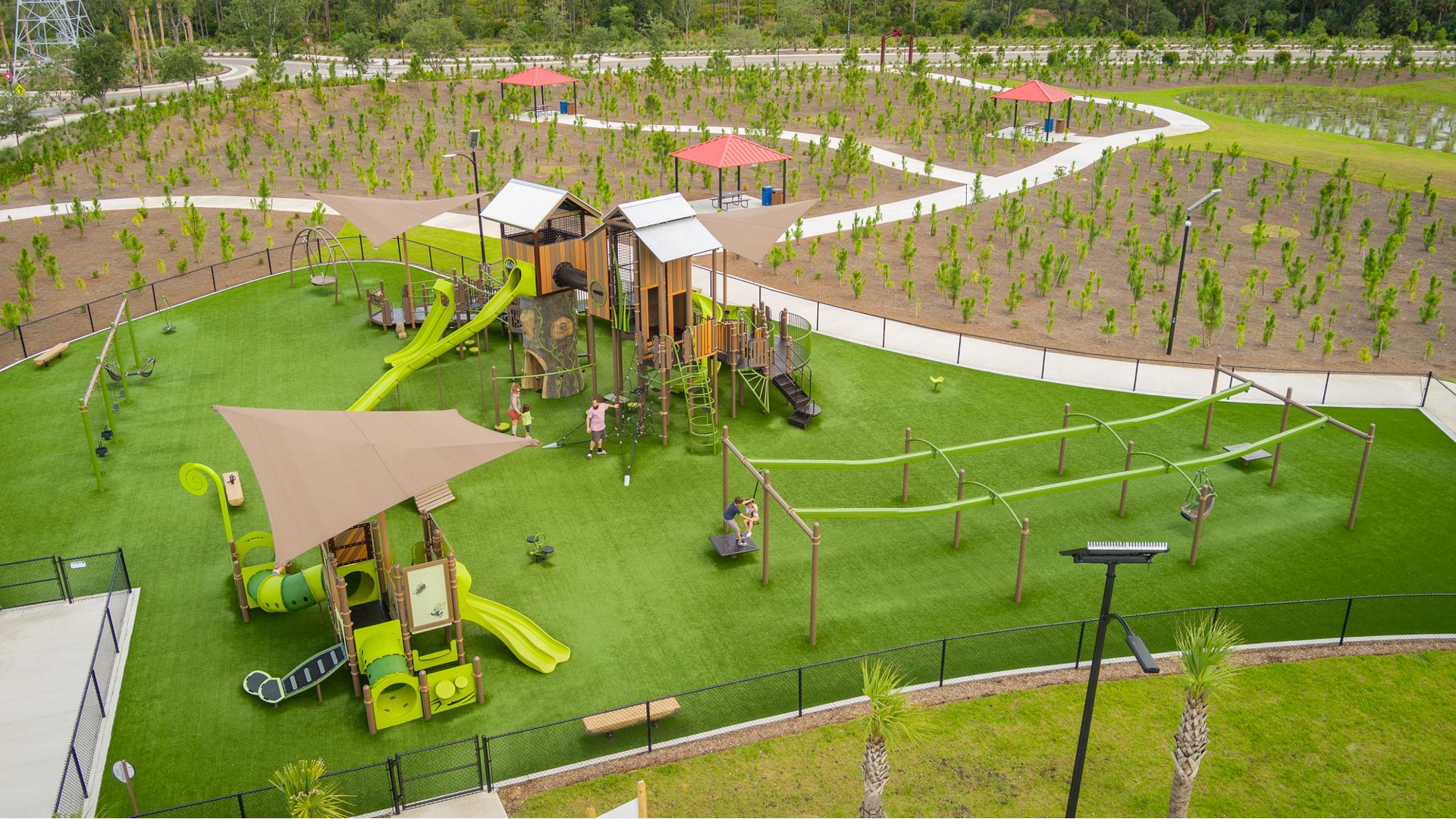 Elevated view of play structures designed like tree houses and other surrounding play activities.