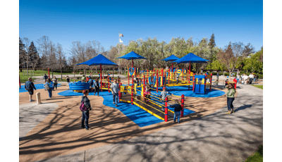 Families playing on primary colored fully-ramped accessible inclusive playground.