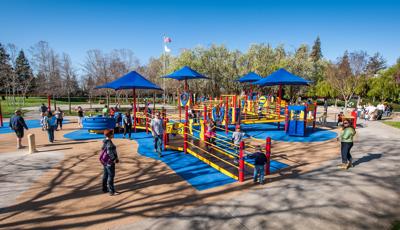 Families playing on primary colored fully-ramped accessible inclusive playground.