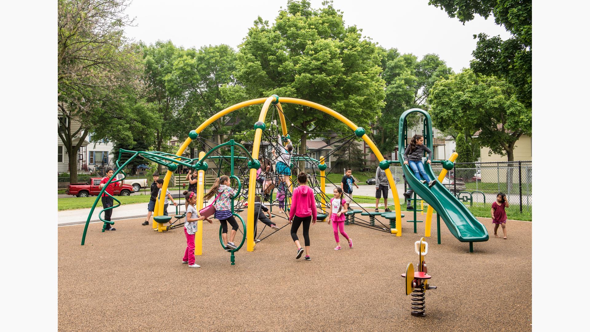 Children playing on a brightly-colored net structure over safety surfacing