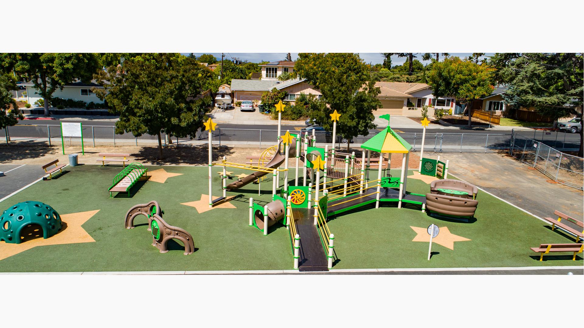 Playground at Ponderosa Elementary in Anaheim, CA. Green & yellow structure with star accents.  Inclusive play/Play Booster structure.