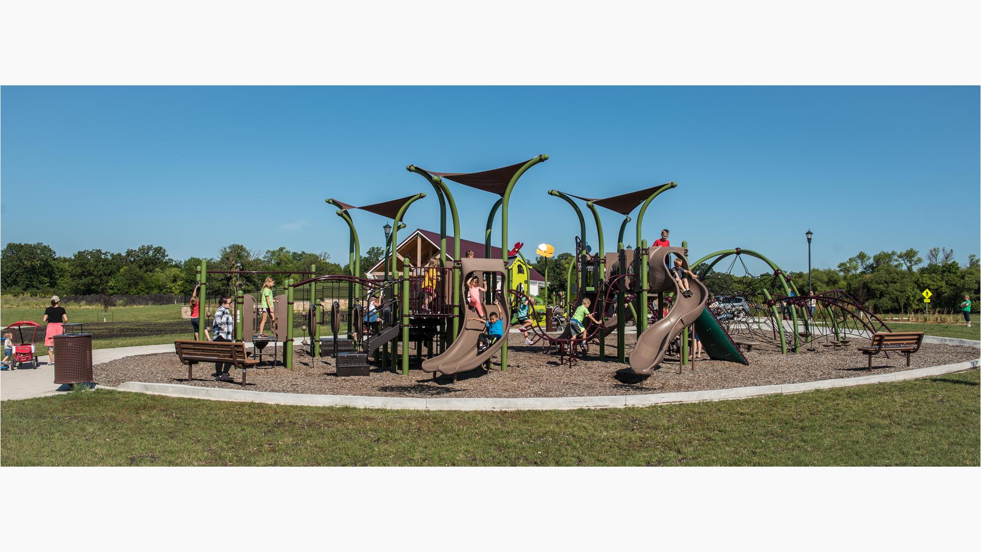 Children playing  in River's Bend park on a sunny day without a cloud in the sky on green grass.