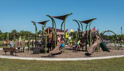 Children playing  in River's Bend park on a sunny day without a cloud in the sky on green grass.