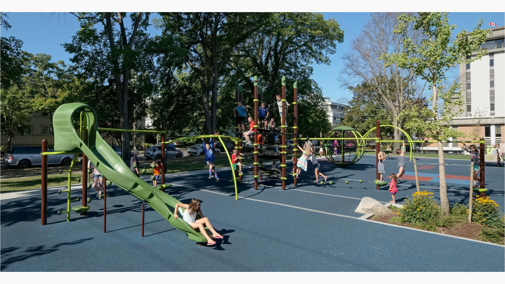 InVictoria Courthouse Playground, a girl is sitting at the bottom of slide . A group of kids swarm on the Netplex structure.