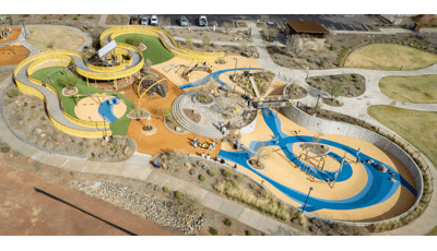 Elevated view of a large community play space with winding accessible ramps leading into play structures.