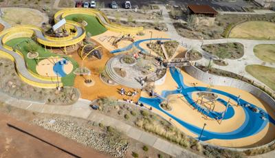 Elevated view of a large community play space with winding accessible ramps leading into play structures.