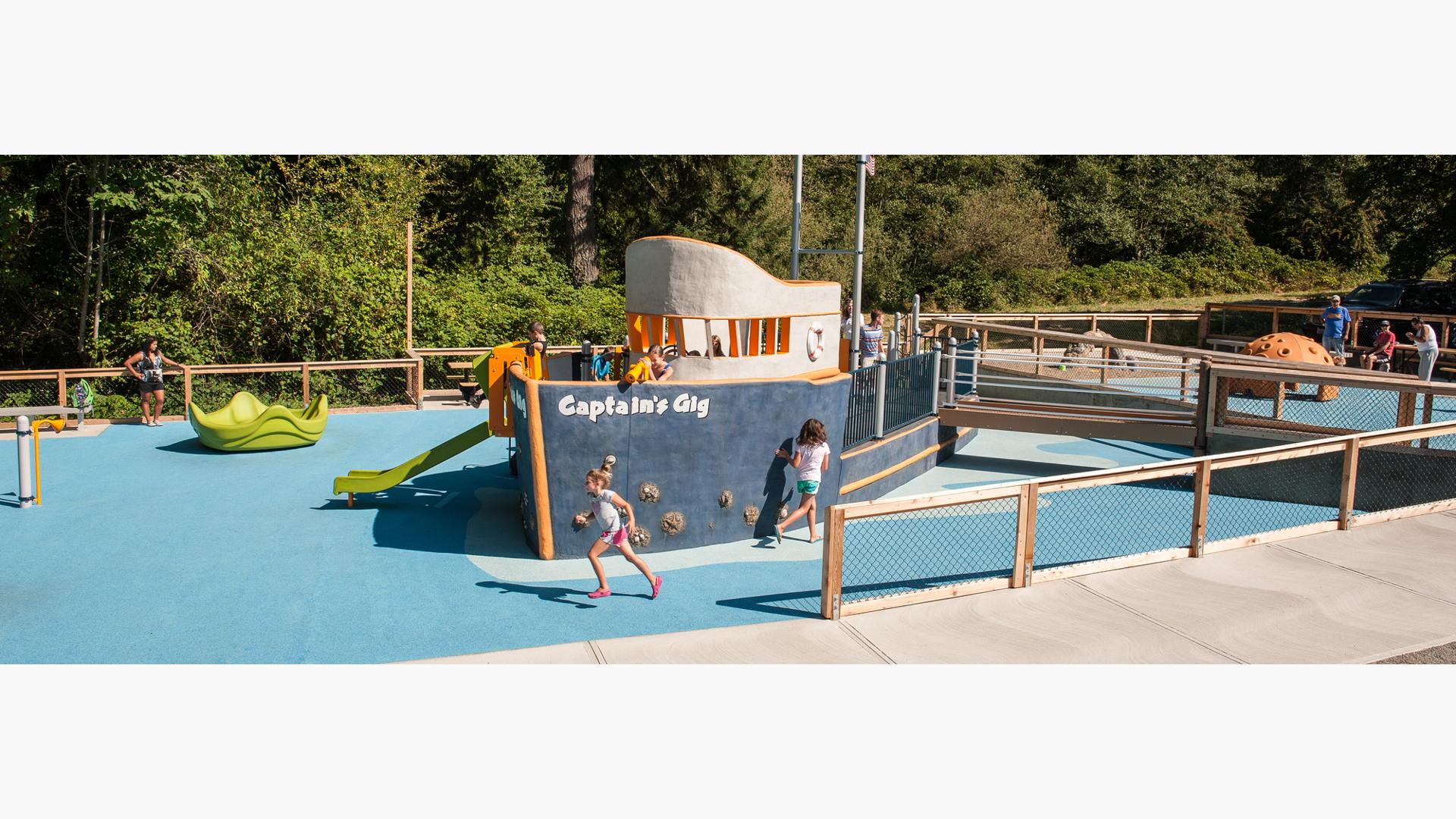 Two girls running in front of boat play structure