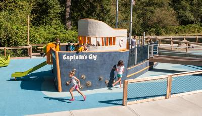 Two girls running in front of boat play structure