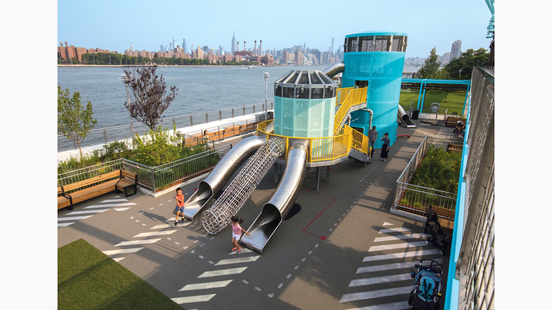 Historic Domino Sugar Factory in Brooklyn, NY turns into a community play space inspired by artist Mark Reigelman with bridge, beautiful colors and stainless steel slides.
