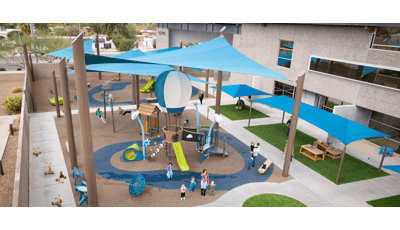Elevated view of large blue shade sails or a playground area next to a building.