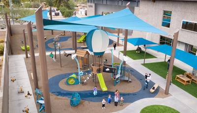 Elevated view of large blue shade sails or a playground area next to a building.