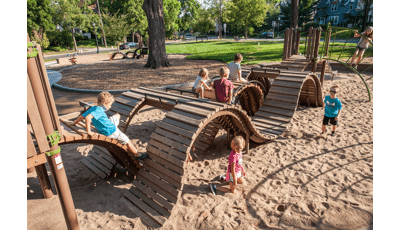 Children climbing over and crawling under custom rolling curves made of wood.