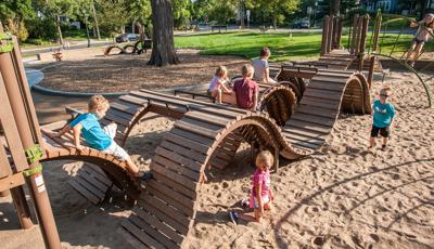 Children climbing over and crawling under custom rolling curves made of wood.